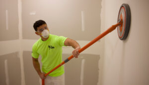 drywall being sanded by a round sander